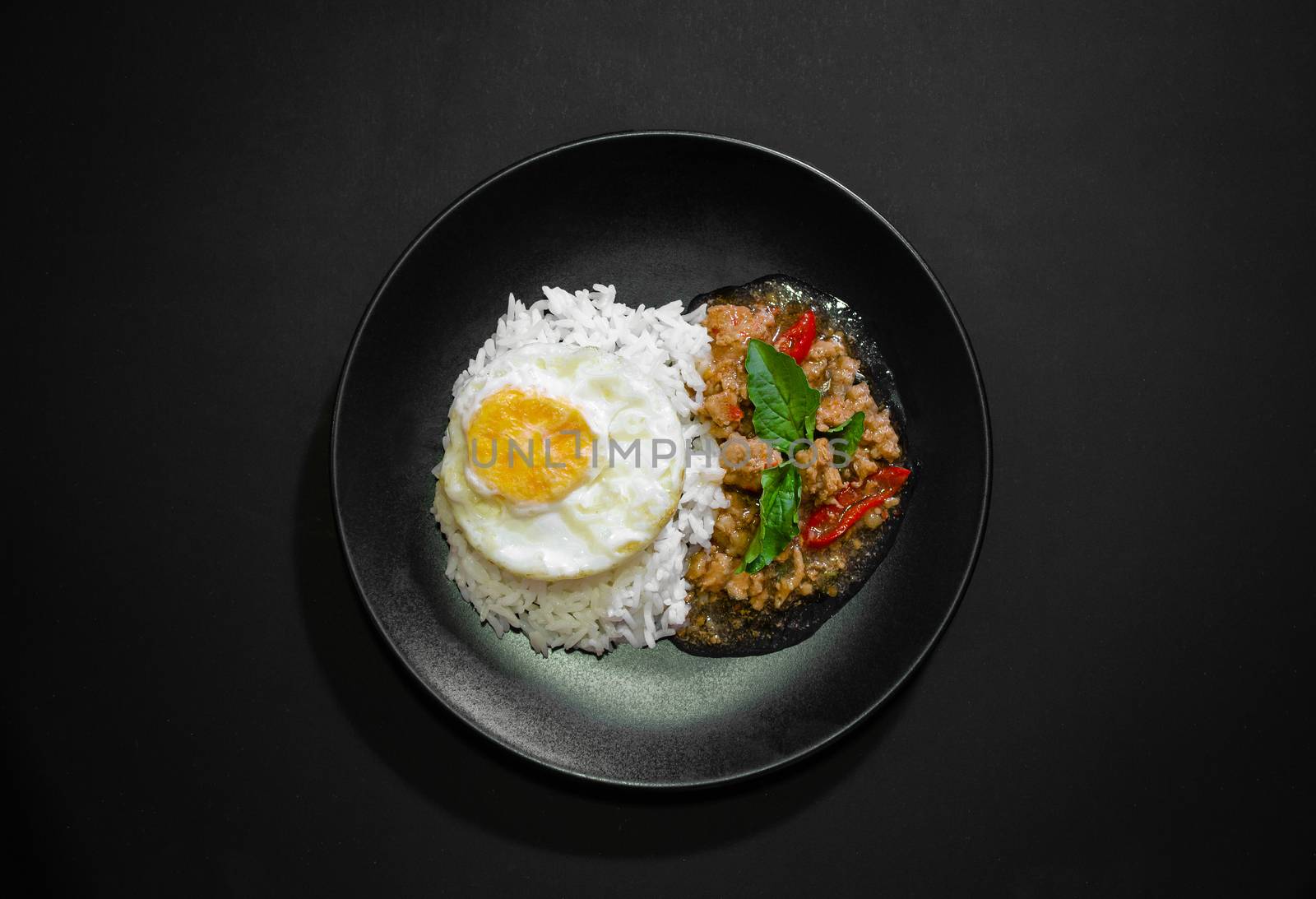 Rice with pork stir fried with basil and fried egg on black background, Thai food, Street food, Image from the top view