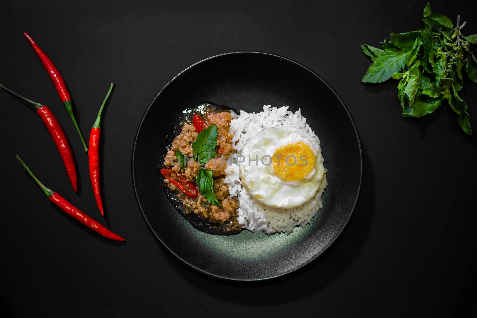 Rice with pork stir fried with basil and fried egg on black background, Thai food, Street food, Image from the top view
