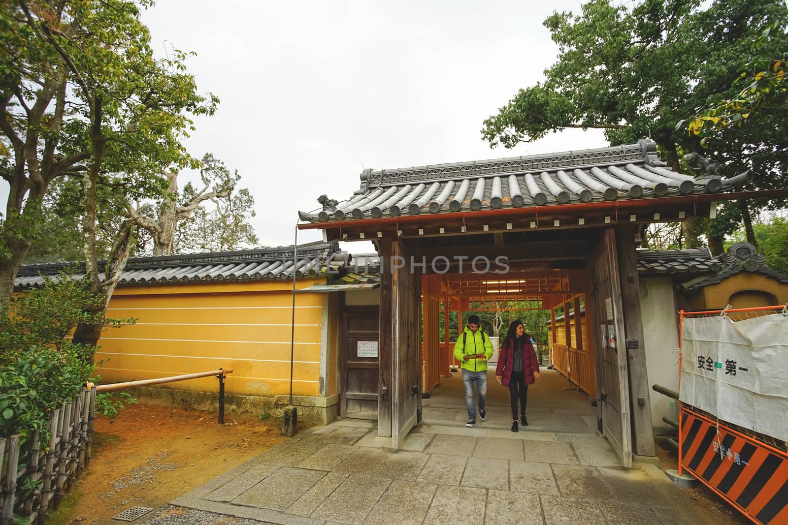 Kyoto, Japan - December 17, 2019 : Tourists walking through the entrance gate of Kinkakuji temple, Kyoto, Japan.