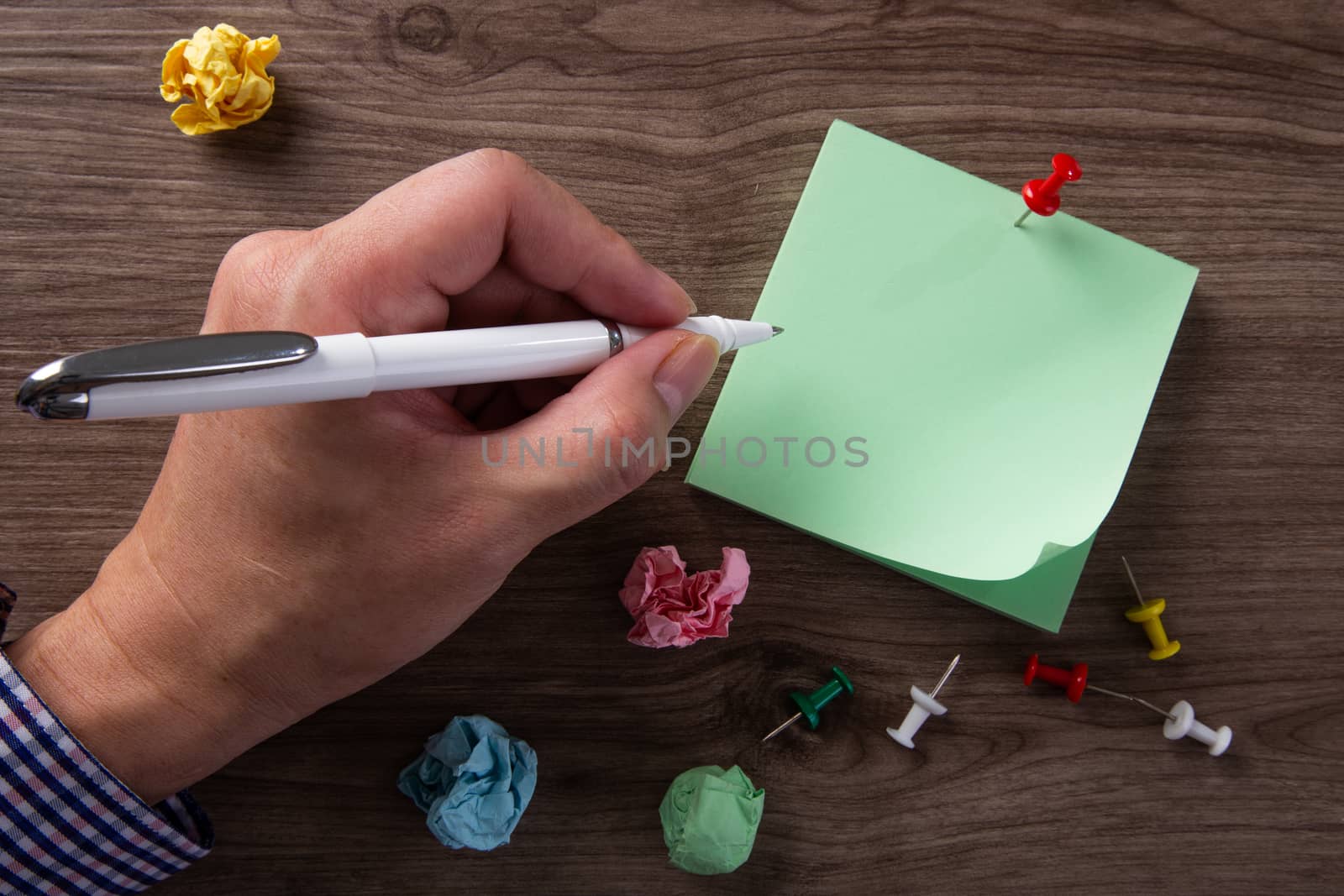 Close up of a hands writes on sticky note pad on a desk.