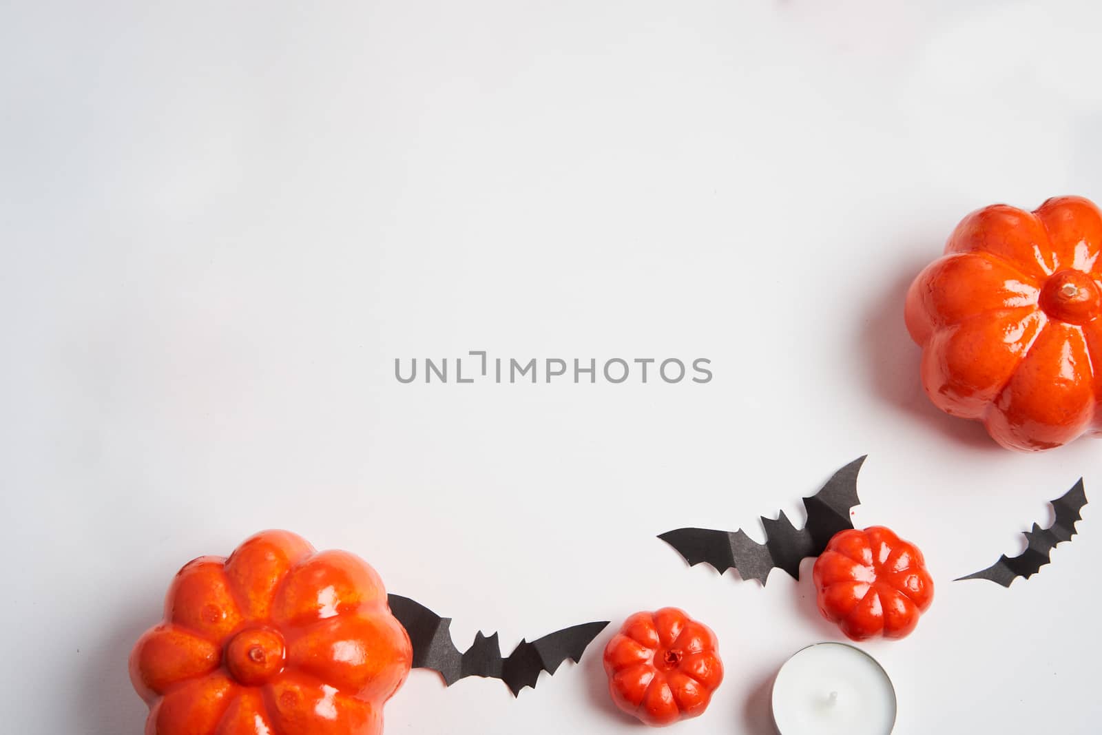 Halloween background, orange decorative plastic pumpkin black paper bat round candle white cardboard Thanksgiving greeting card pattern