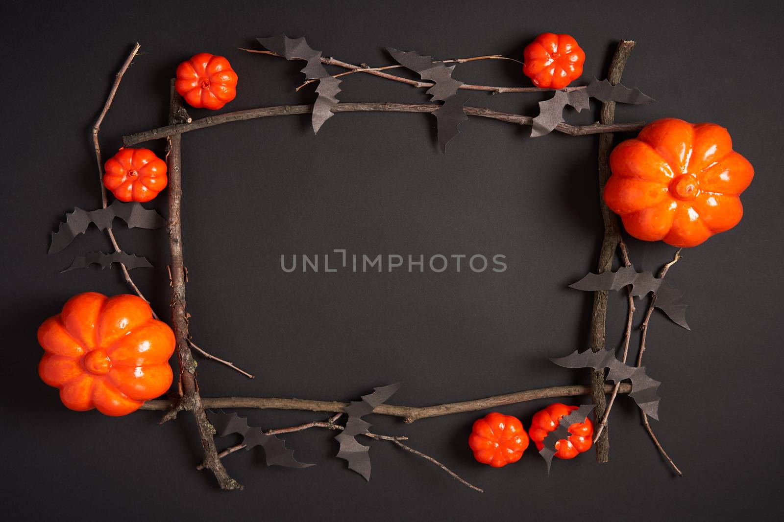 Halloween background, orange decorative plastic pumpkin black paper bat dry branch stick square frame black cardboard Thanksgiving greeting card pattern