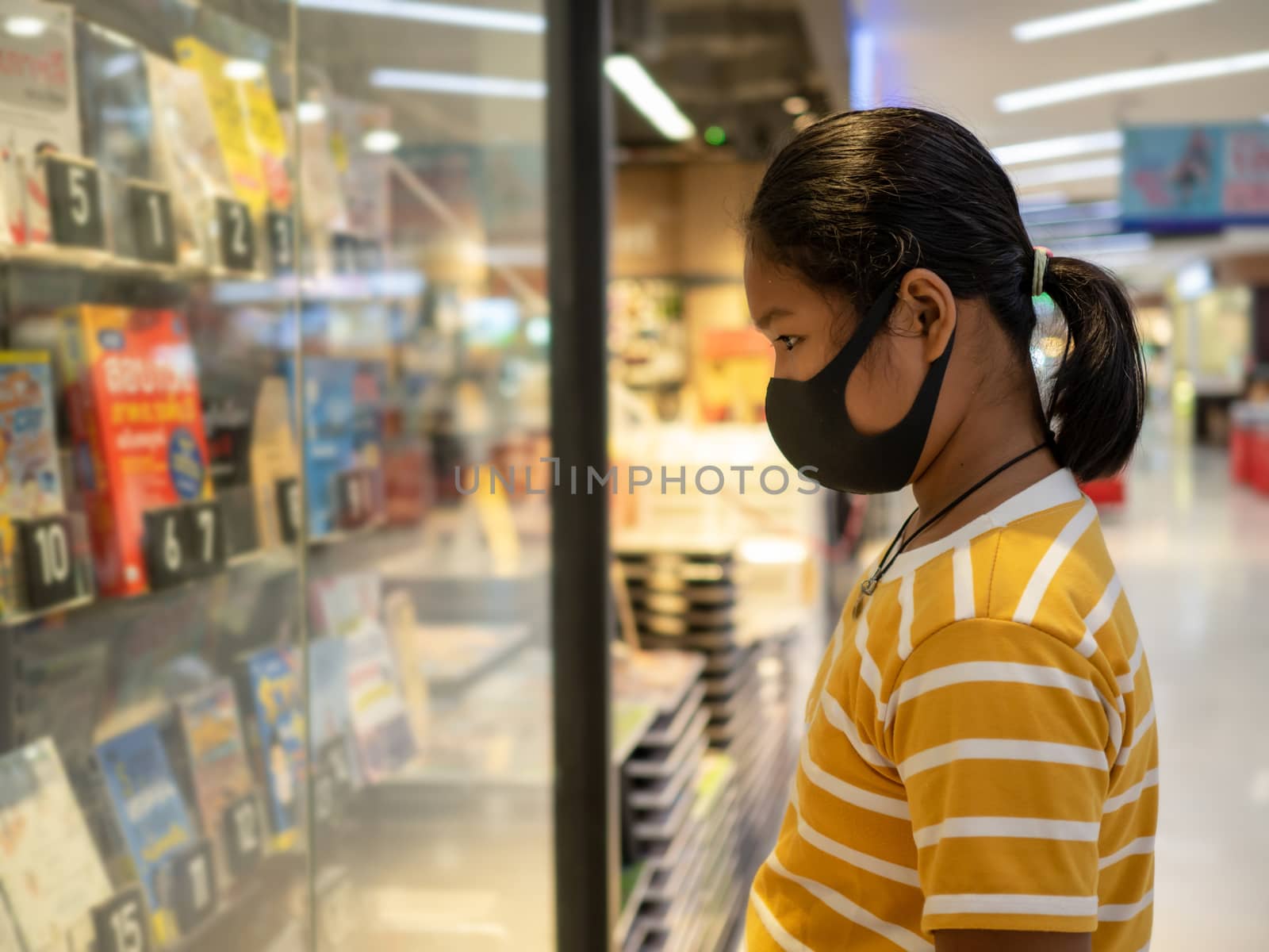 Long haired girl Wear a protective mask Looking at the showcase In a bookstore. Concept of life And protect yourself from the coronavirus outbreak.