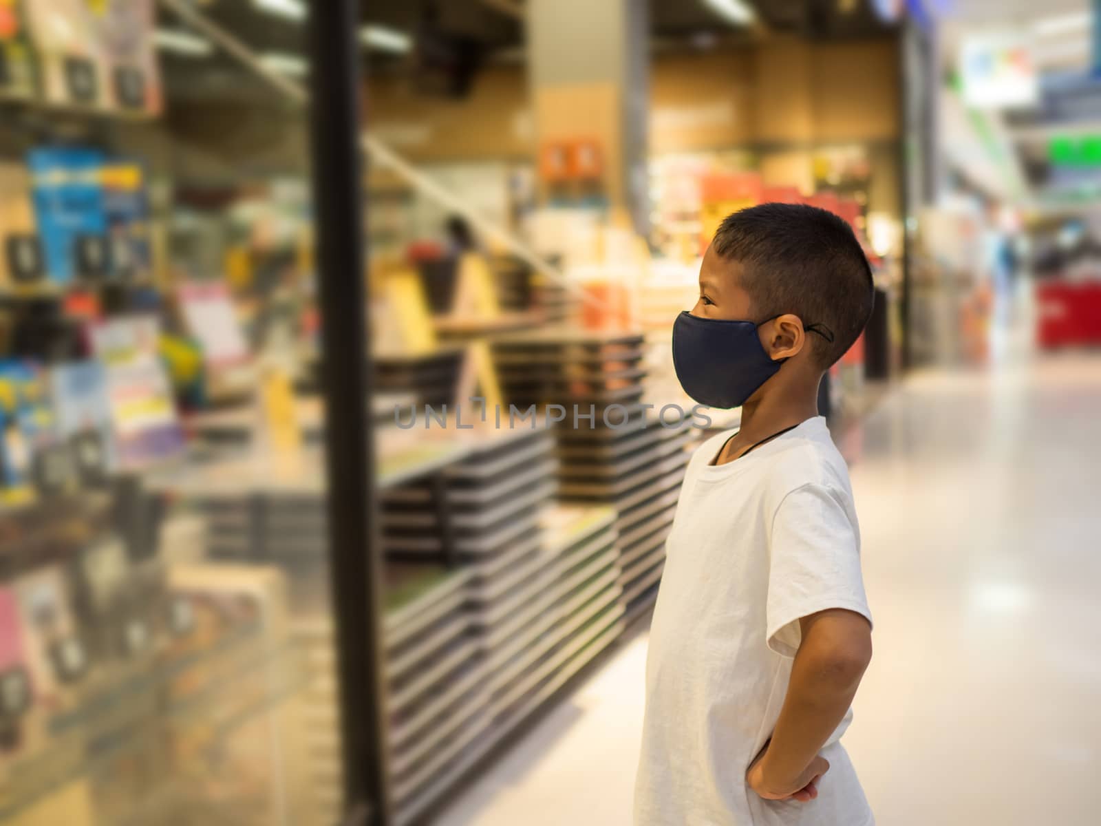 A boy wear a protective mask Looking at the showcase In a bookstore. Concept of life And protect yourself from the coronavirus outbreak.