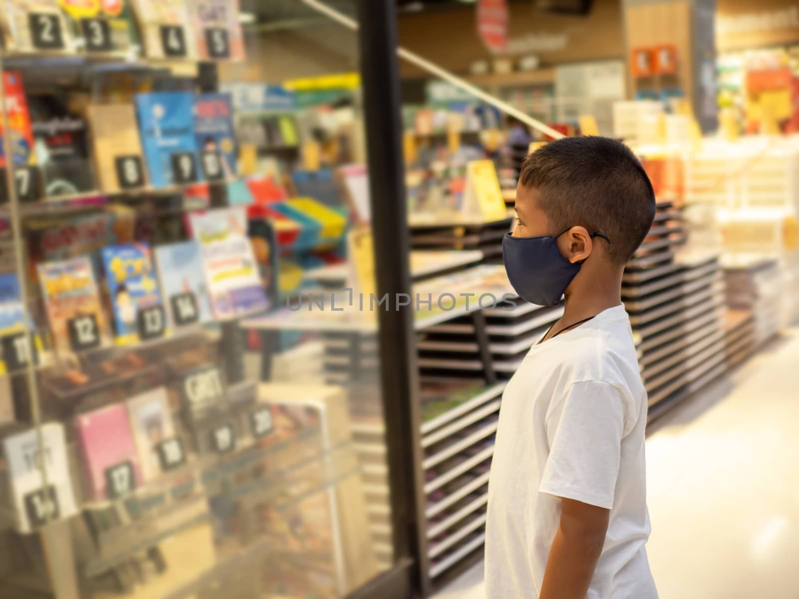 A boy wear a protective mask Looking at the showcase In a bookstore. Concept of life And protect yourself from the coronavirus outbreak.