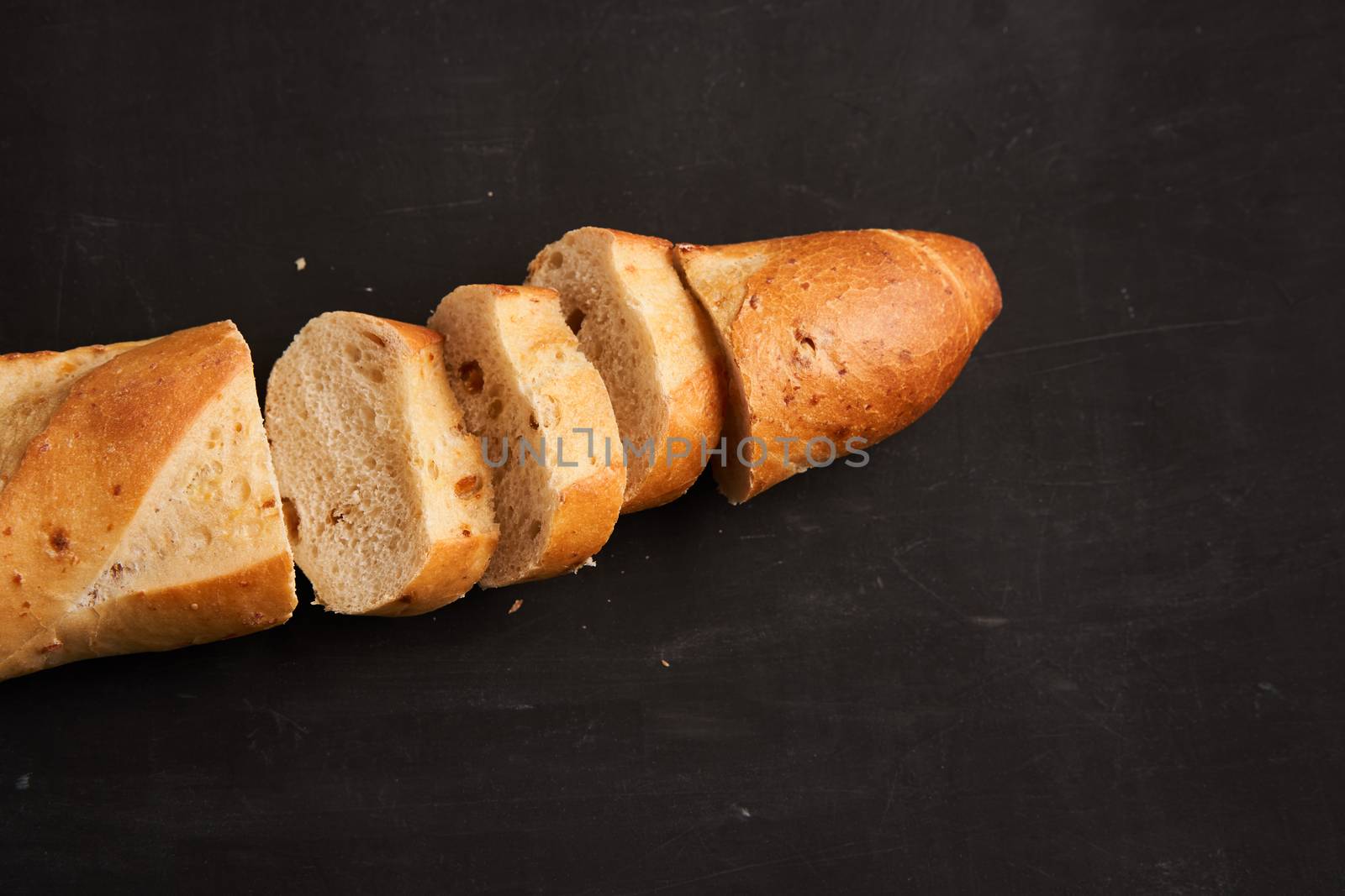 one sliced crispy french baguettes lie dark black table background sesame seeds Classic french national pastries Copy space Concept for menu or advertising