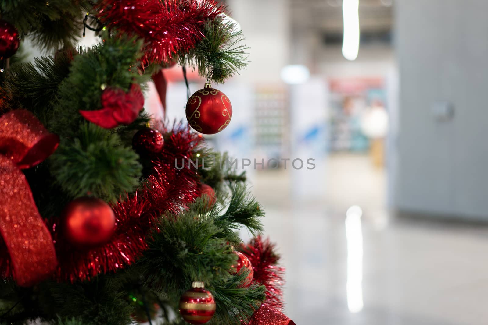 Close Christmas tree in a shopping center against the background of blurry shop windows. Free space for text
