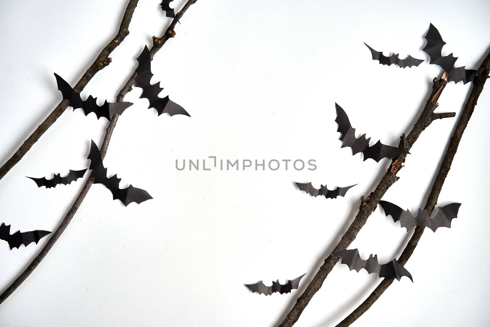 Halloween decoration concept black paper bats dry branch stick white cardboard background With copy space for tetxt