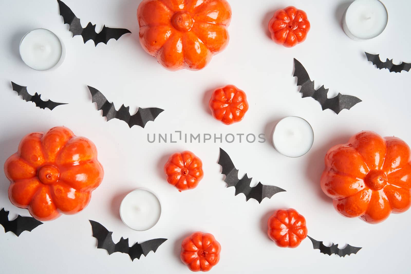 Halloween background, orange decorative plastic pumpkin black paper bat round candle white cardboard Thanksgiving greeting card pattern