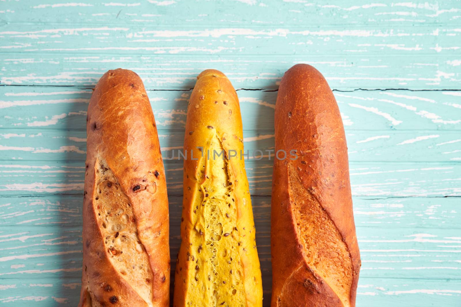 Three crispy french baguettes lie blue wooden background baguettes in assortment with sesame seeds Classic french national pastries Copy space Concept for menu or advertising