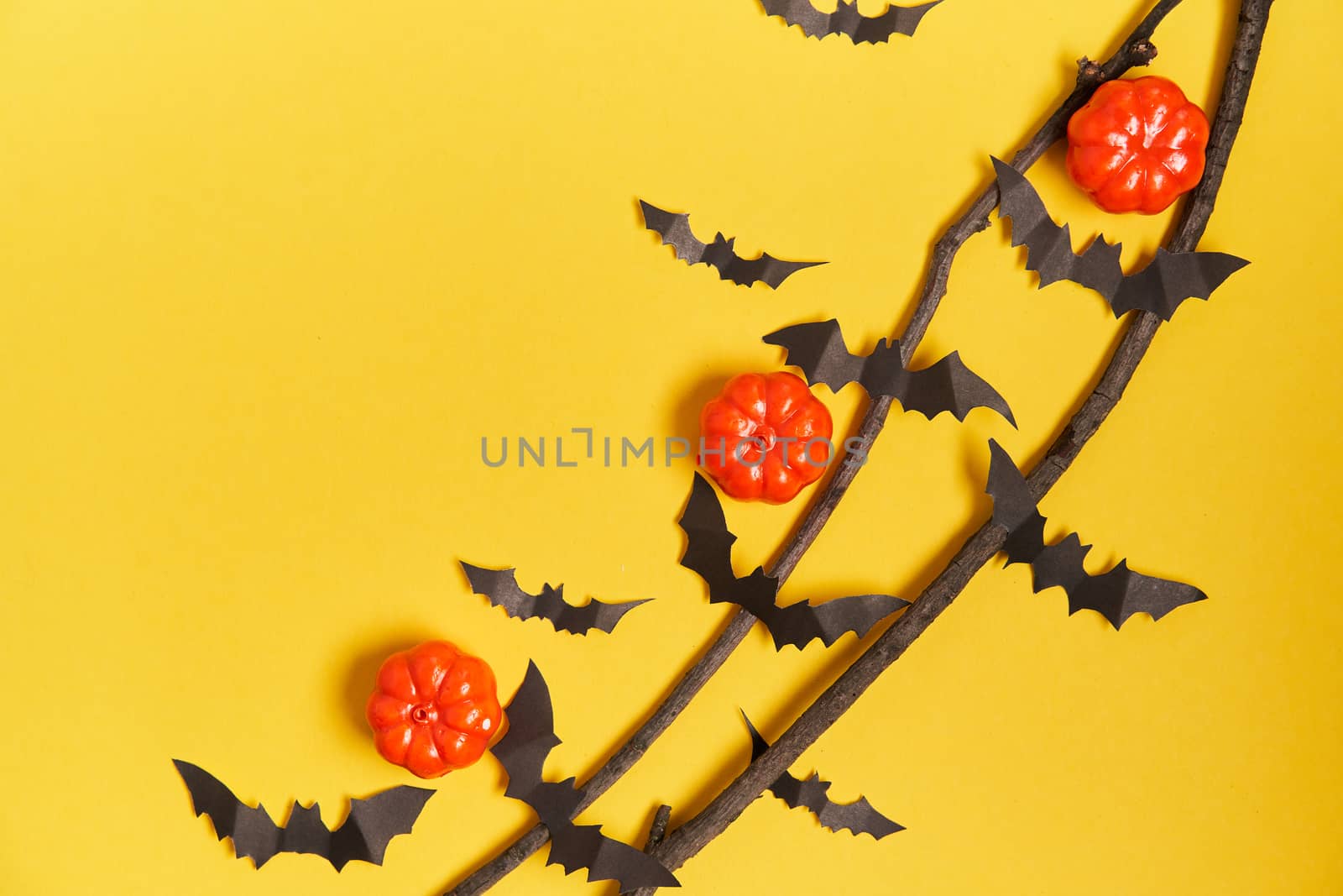 Halloween background, orange decorative plastic pumpkin black paper bat dry branch stick yellow cardboard Thanksgiving greeting card pattern