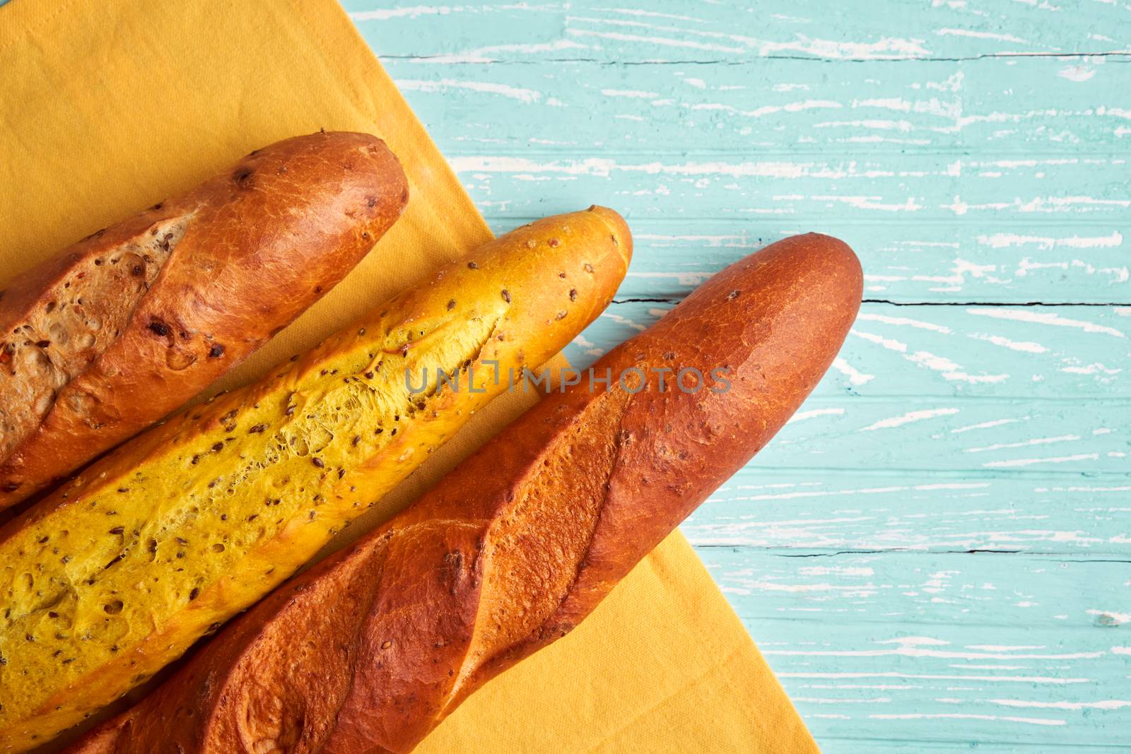 Three crispy french baguettes lie blue wooden background baguettes in assortment with sesame seeds Classic french national pastries Copy space Concept for menu or advertising