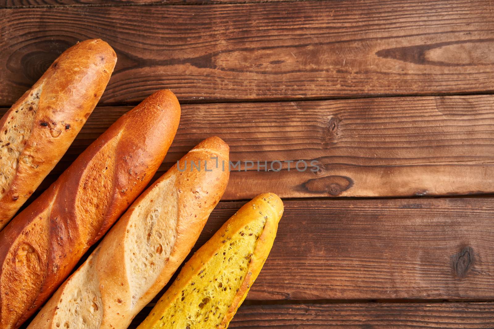 Three crispy french baguettes lie on an old wooden table with free space for text baguettes in assortment with sesame seeds Classic french national pastries Copy space Concept for menu or advertising