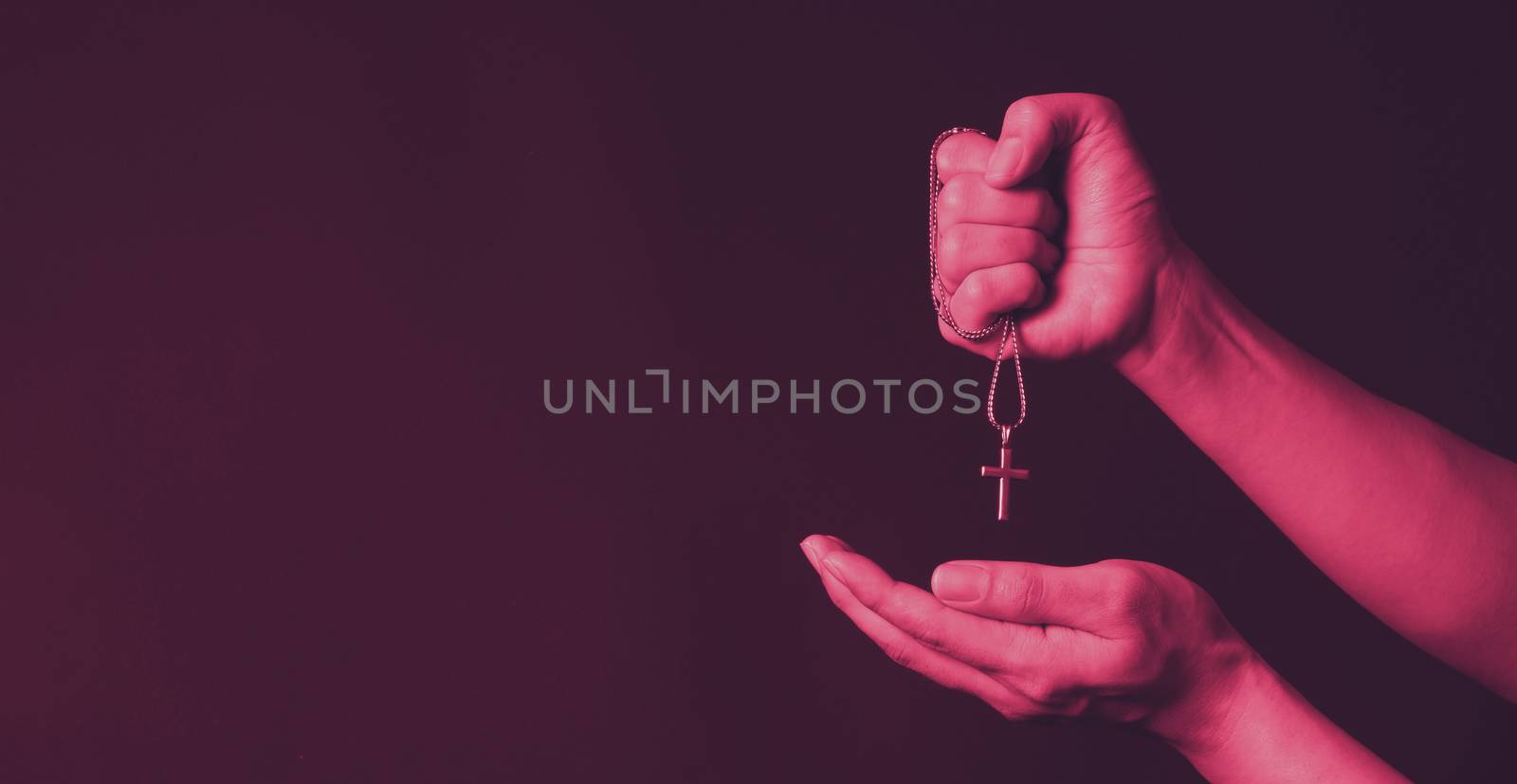 Crucifix pendant or cross sign made from silver and hold in man hand. represent praying for someone that pass away from World pandemic coronavirus and close-up shot black background 