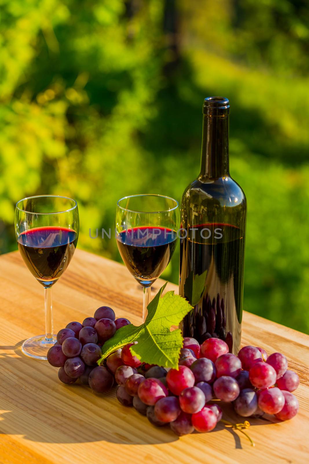 wine bottle and grapes on wooden table, outdoor