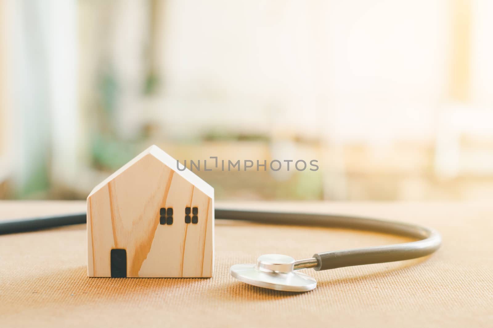Home repair and inspector concept. Stethoscope and wooden home model. Checking house and real estate with sunlight.