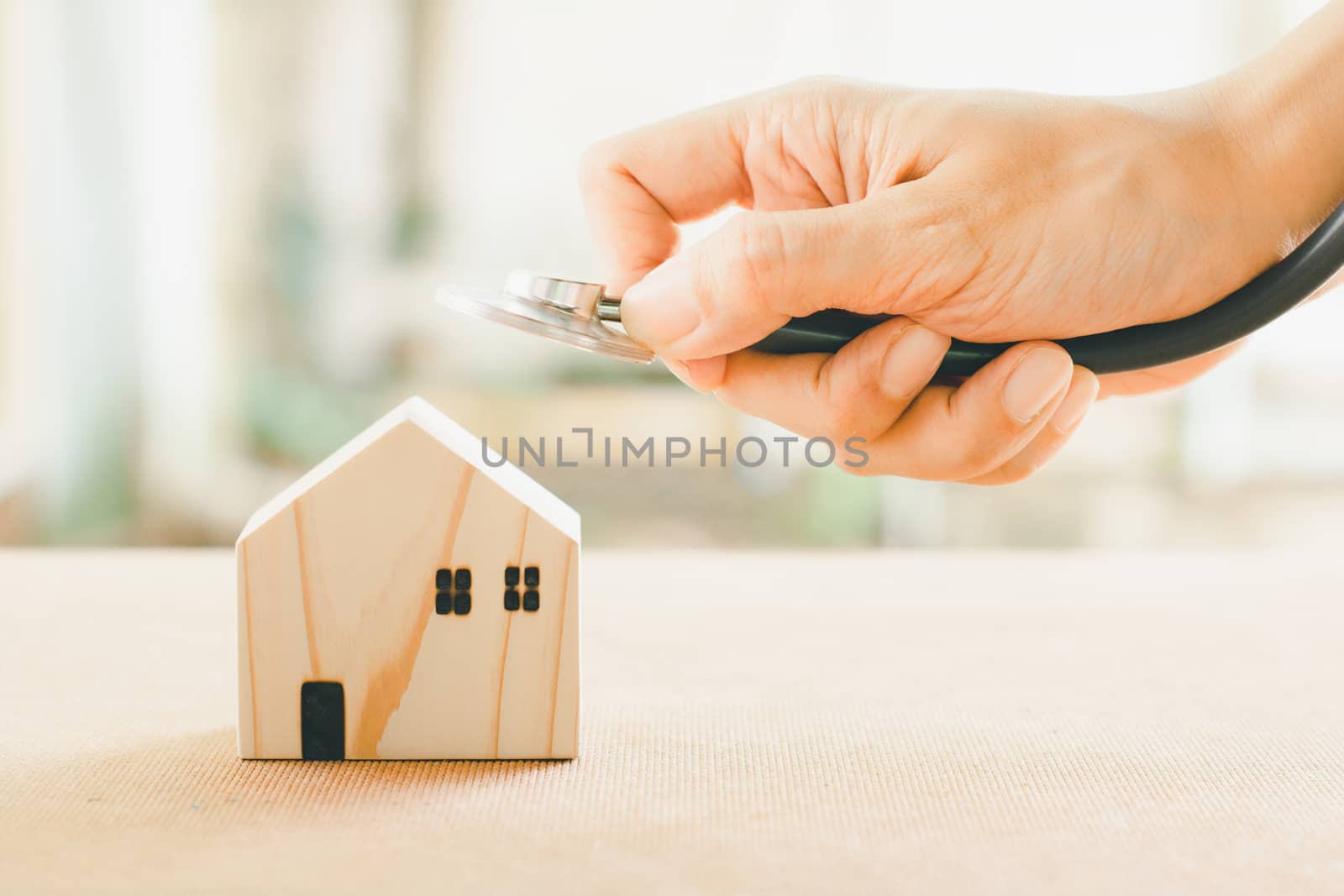 Home repair and inspector concept. Hand holding stethoscope checking on wooden home. 