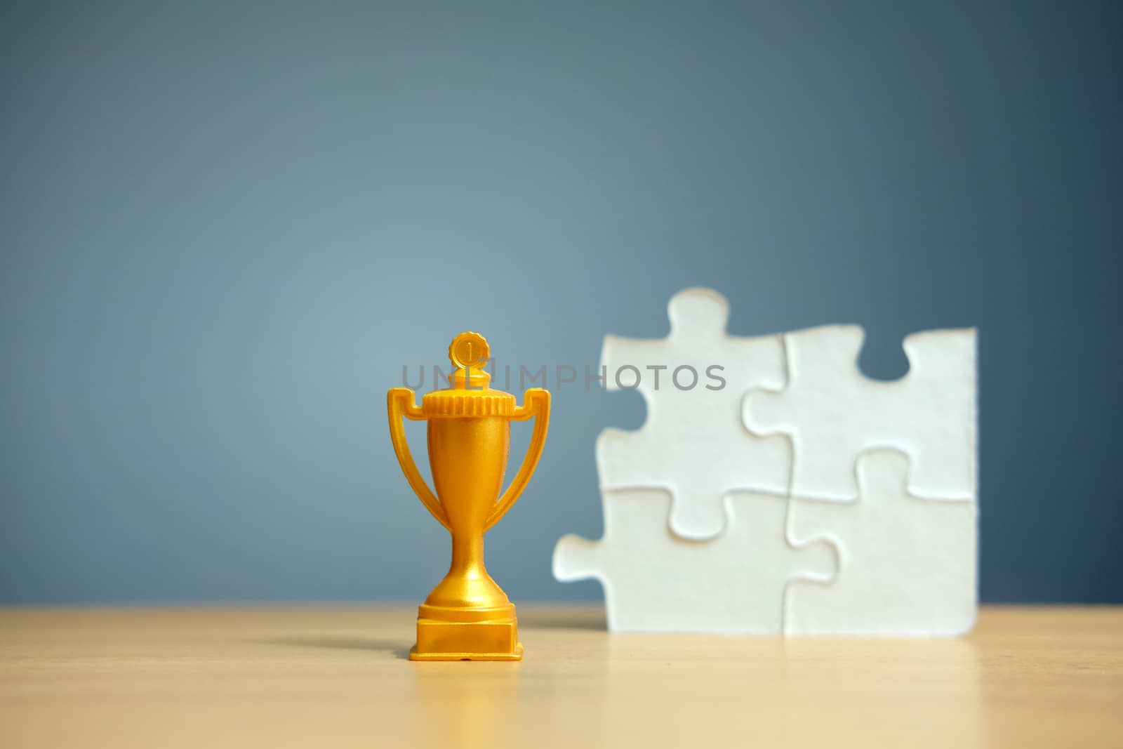 Golden trophy with white puzzle on a wooden table