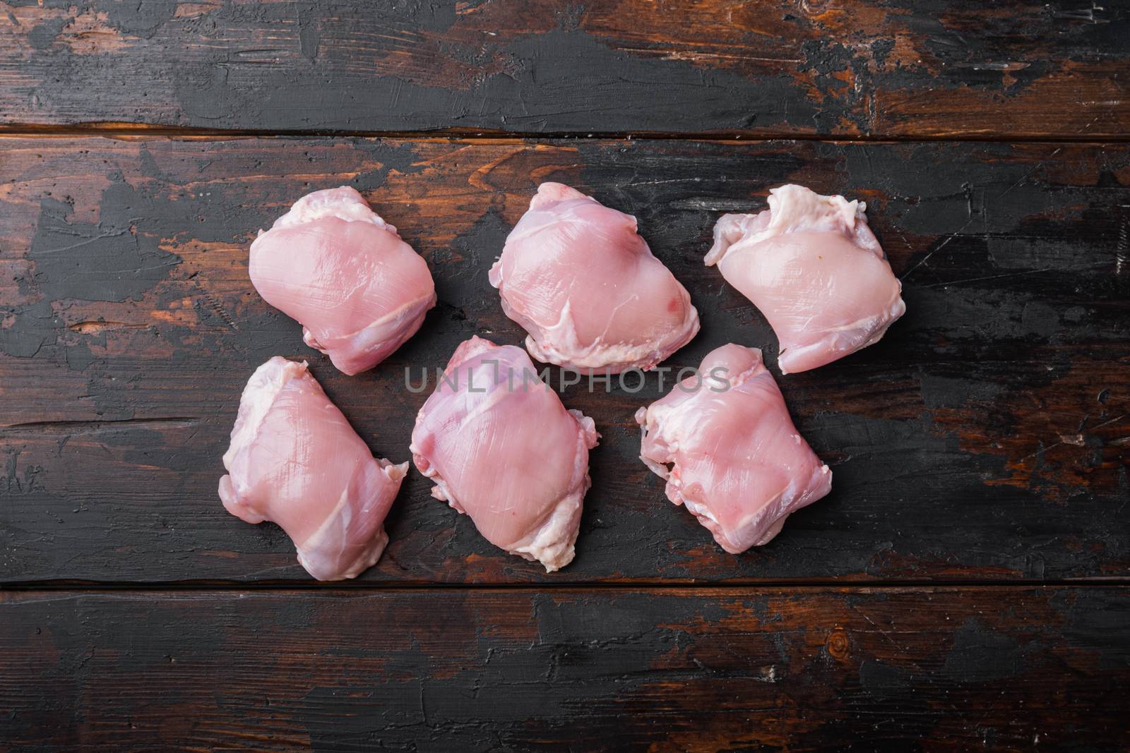 Organic skinless chicken thighs on wooden tabletop viewwith space for text.