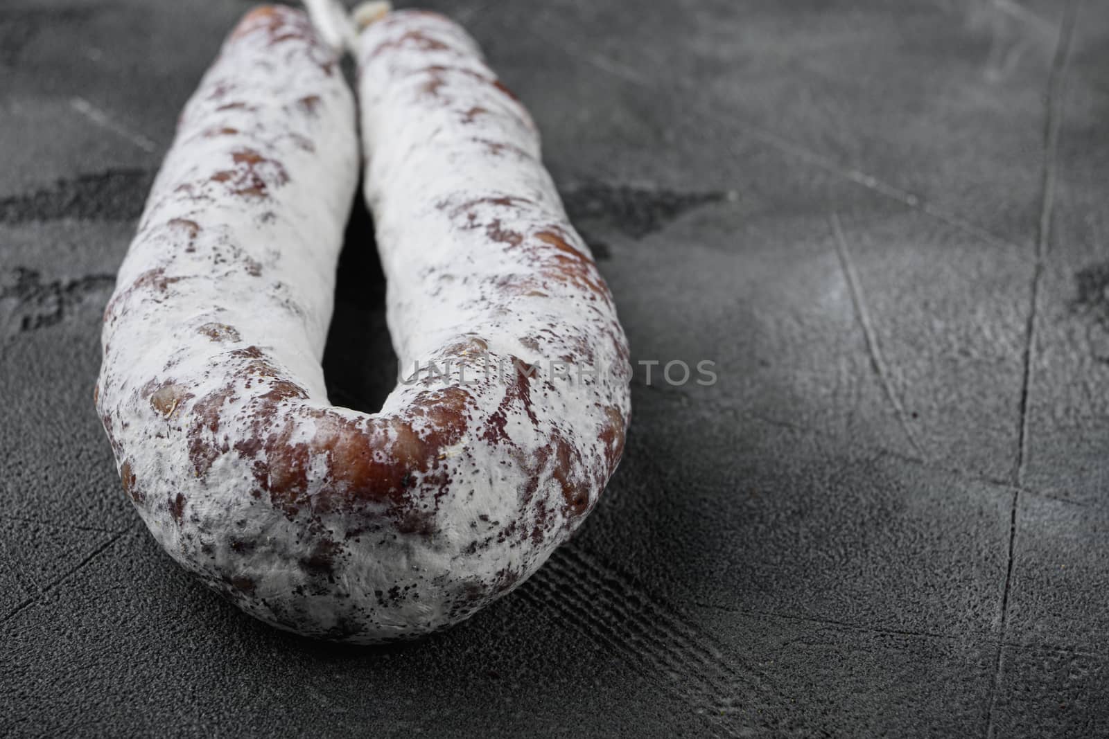 Dry cure salami sausage fuet on grey background with space for text.
