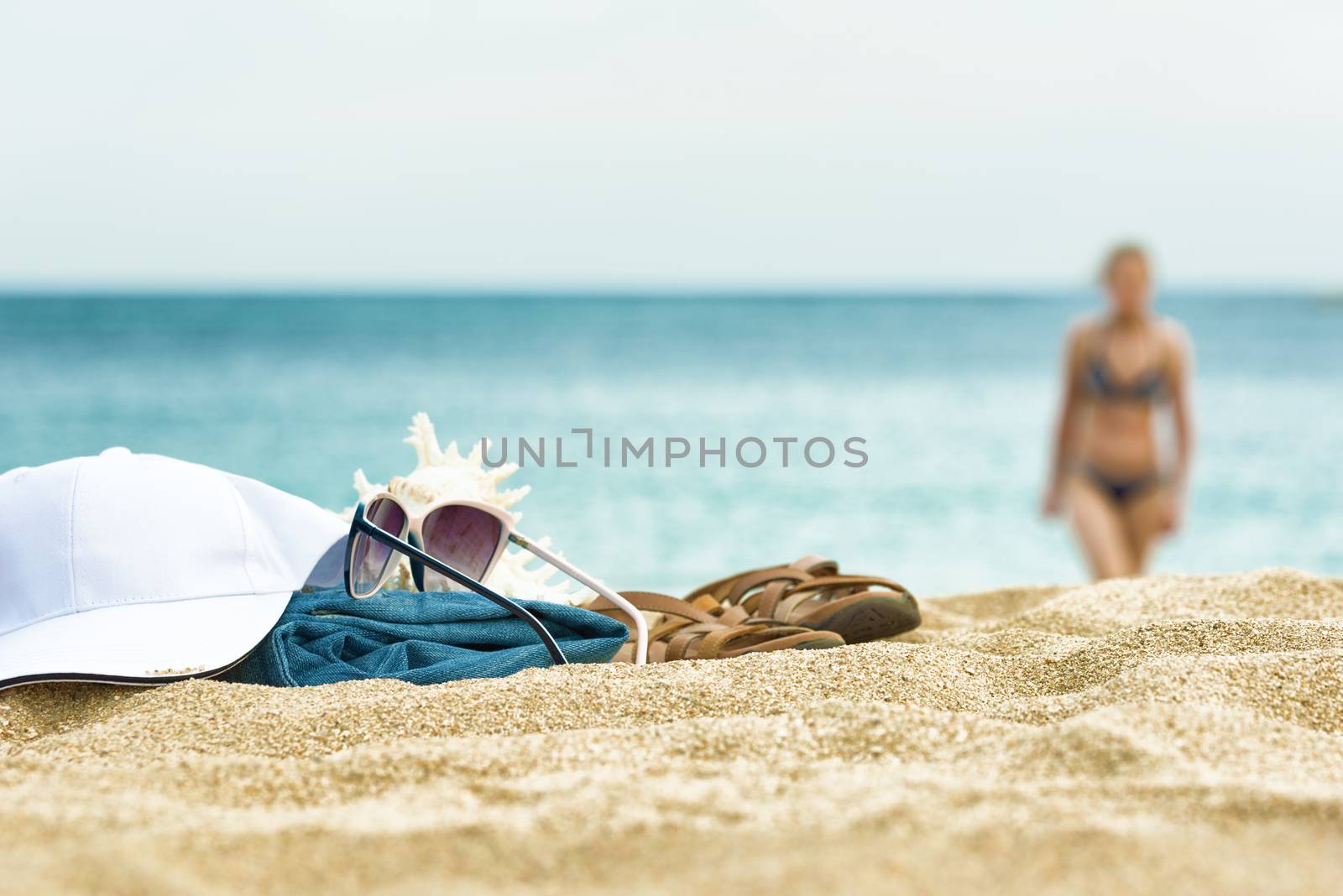 Clothing and glasses on the beach sand. Silhouetted girls in swimsuit on the beach