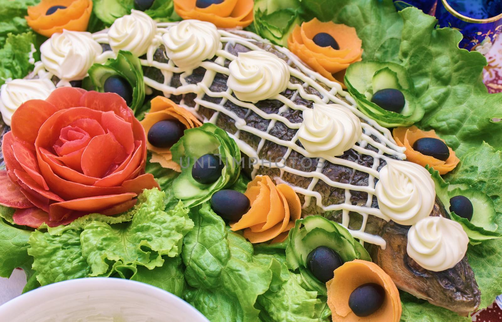 Baked fish decorated with vegetables. Fish and vegetables on the table.