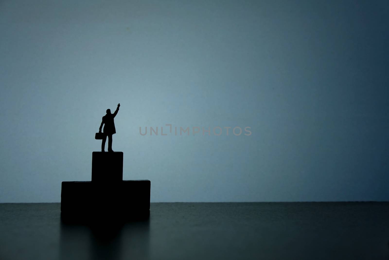 Business strategy conceptual photo - Silhouette of miniature businessman standing on podium while pointing upside