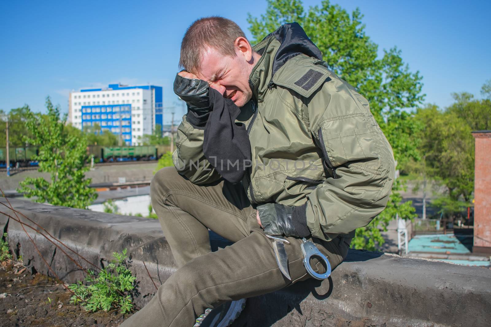 Crying military man and wiping his tears on a black balaclava