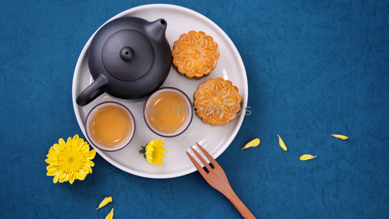 Moon cake for Mid-Autumn Festival, delicious beautiful fresh mooncake on a plate over blue background table, top view, flat lay layout design concept.