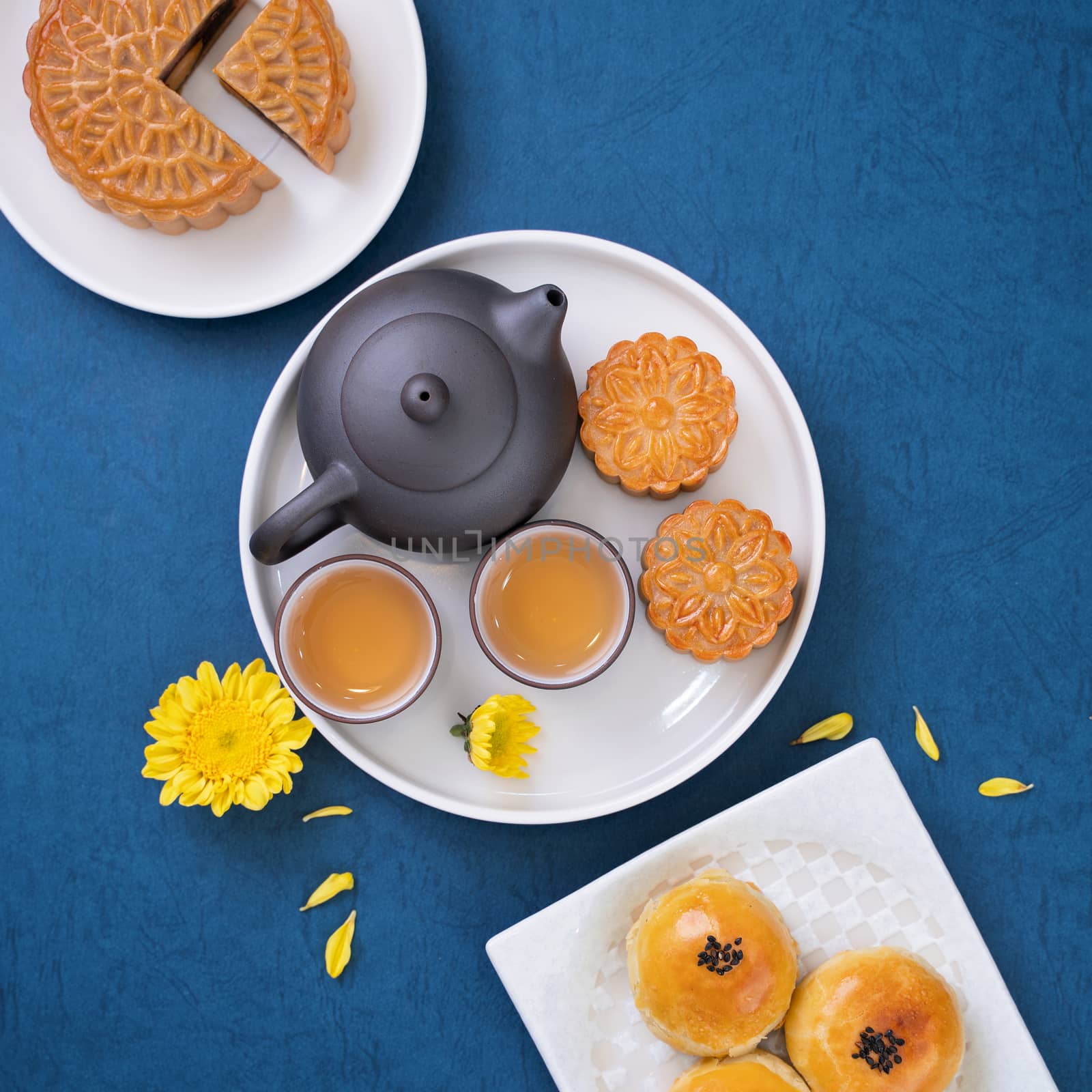 Moon cake for Mid-Autumn Festival, delicious beautiful fresh mooncake on a plate over blue background table, top view, flat lay layout design concept.