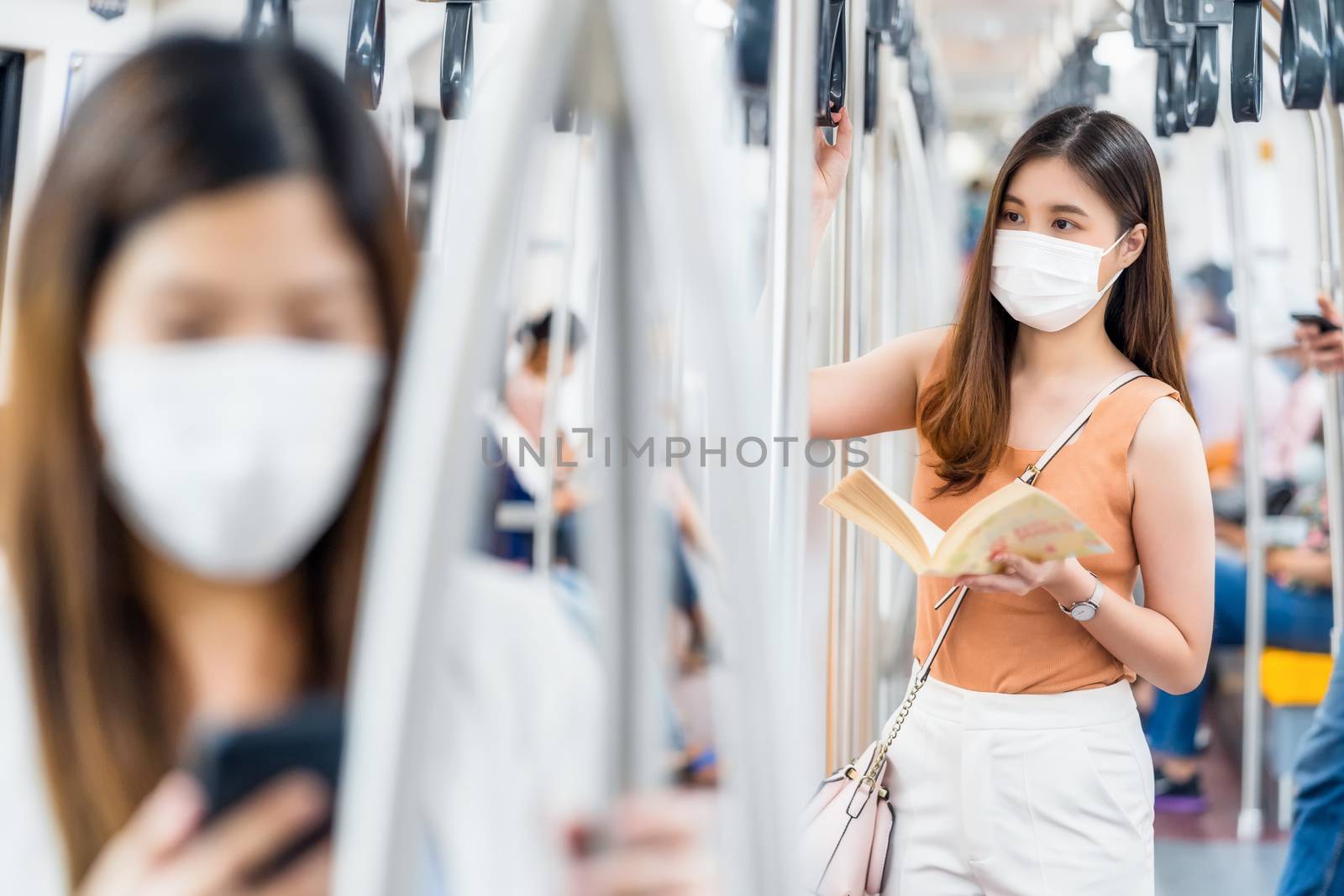 Young Asian woman passenger wearing surgical mask and reading th by Tzido