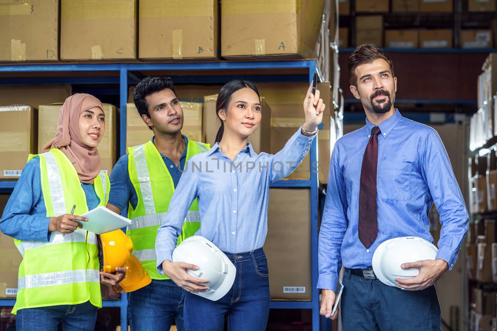 Group of Diversity warehouse worker checking and pointing to product when walking and meeting in local warehouse, muslim, indian, white caucasian and asian people working in export industry concept