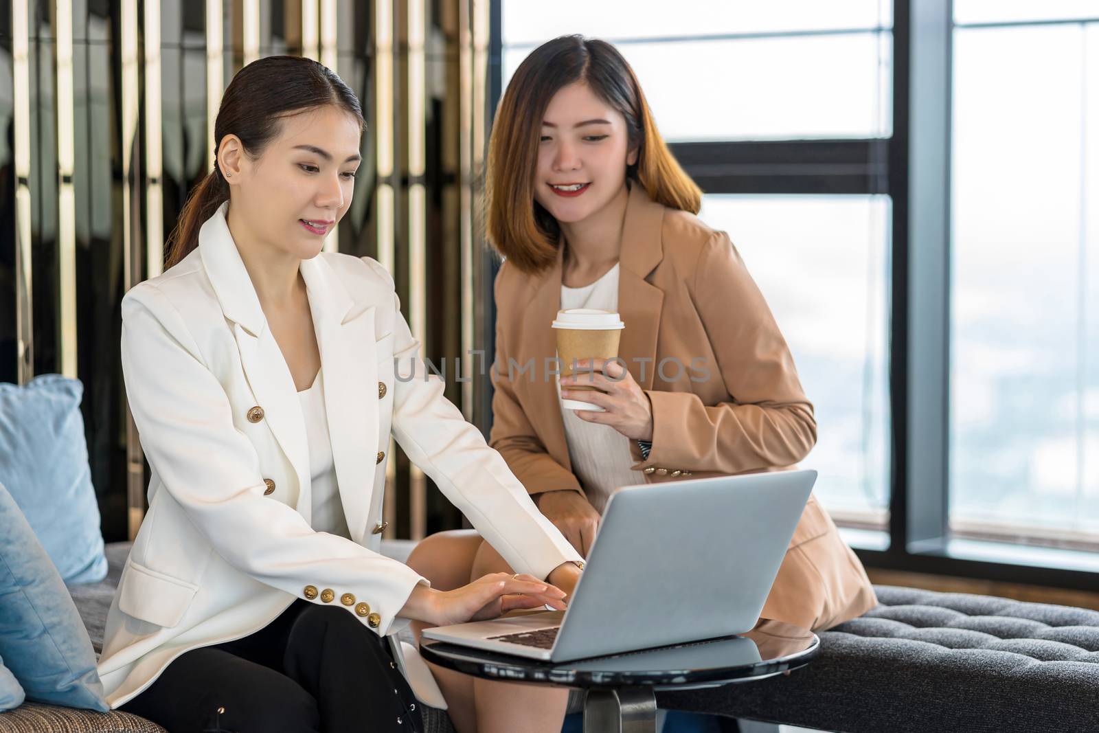 Two asian businesswomen working with the partner business via technology laptop in modern meeting room, office or working space, coffee break, partner and colleague concept by Tzido