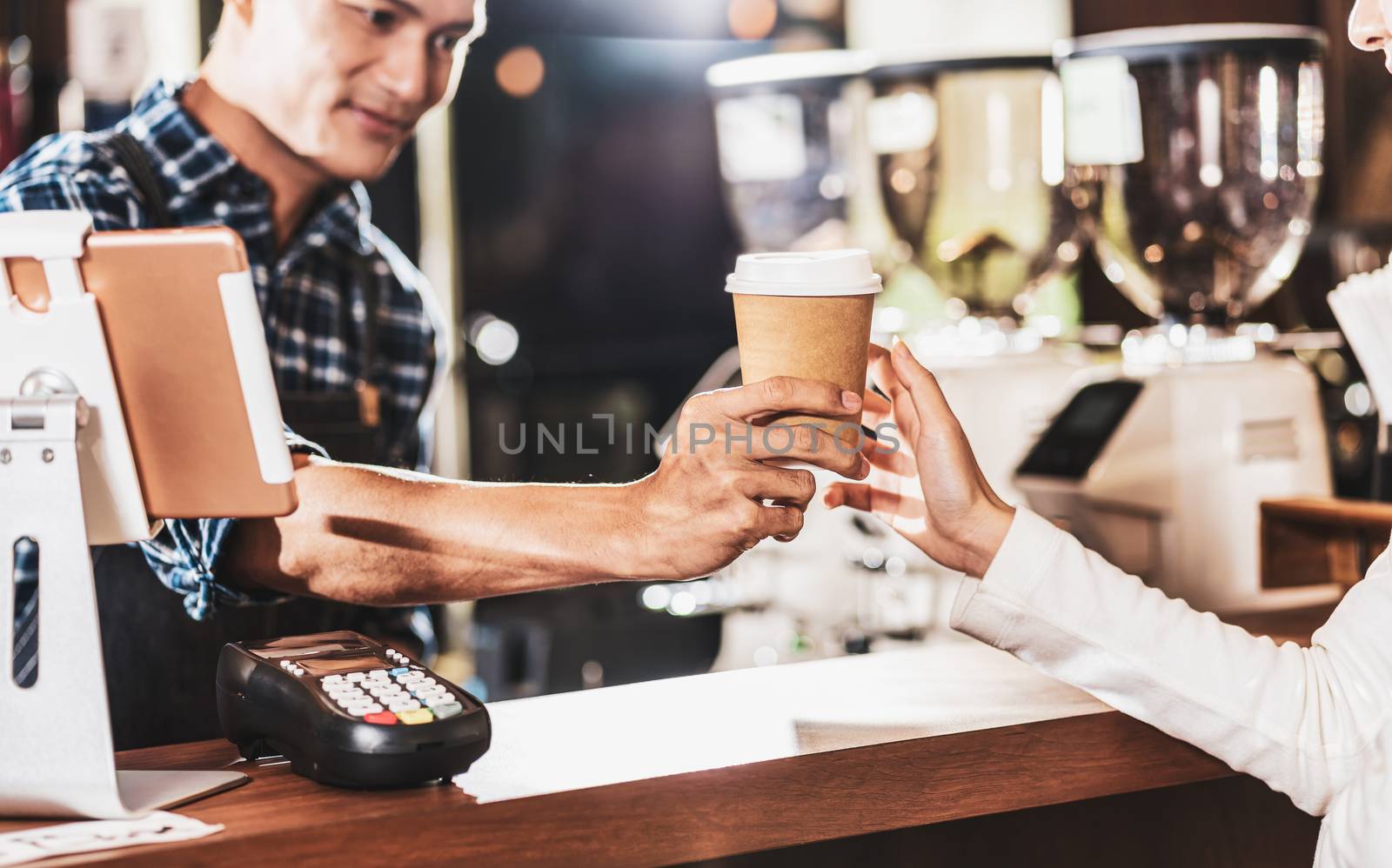 Asian Barista serving a paper cup of coffee to customer in coffe by Tzido