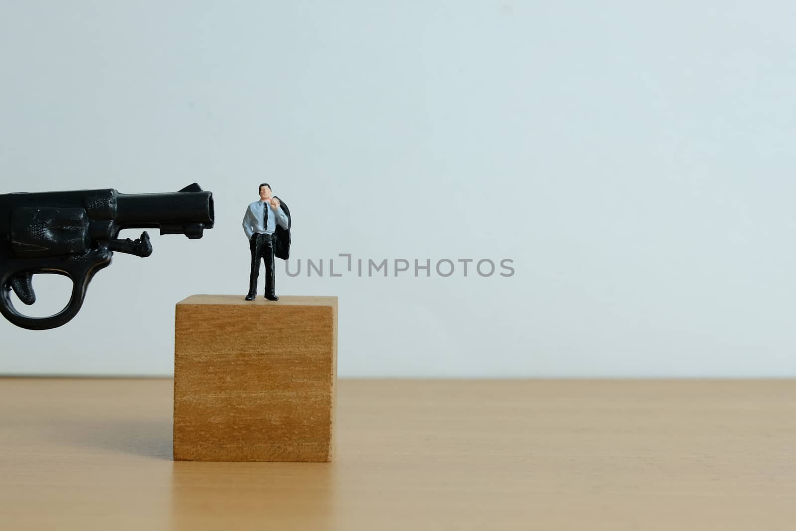 Miniature people concept - businessman standing on wooden block, thinking to death for debt solution