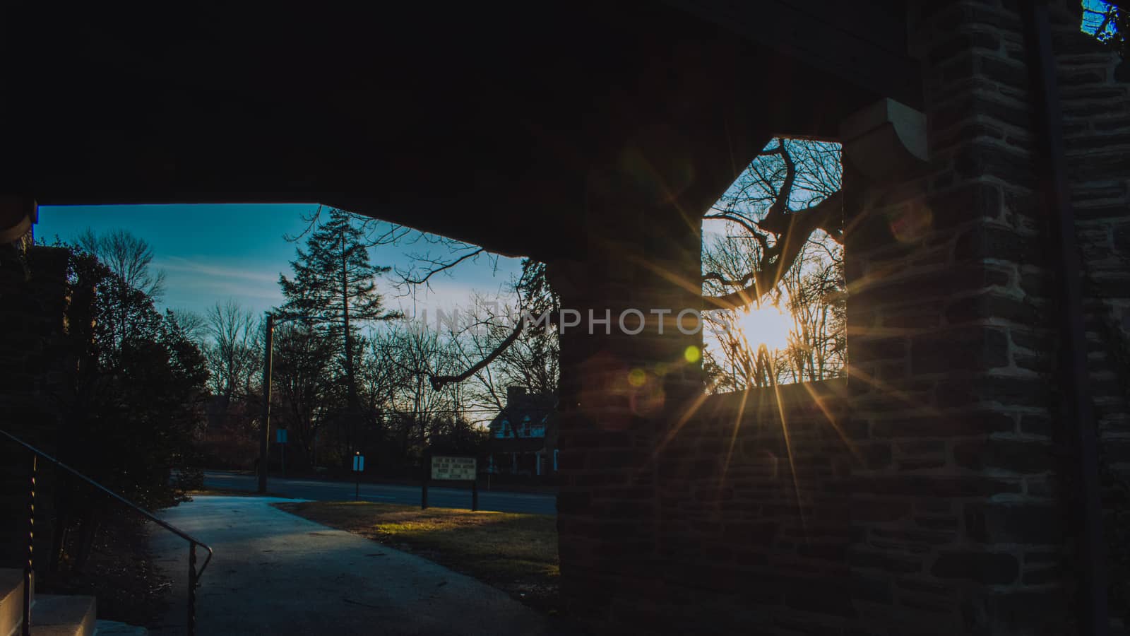 The Sun Shining Through a Window in a Cobblestone Wall in a Suburban Neighborhood