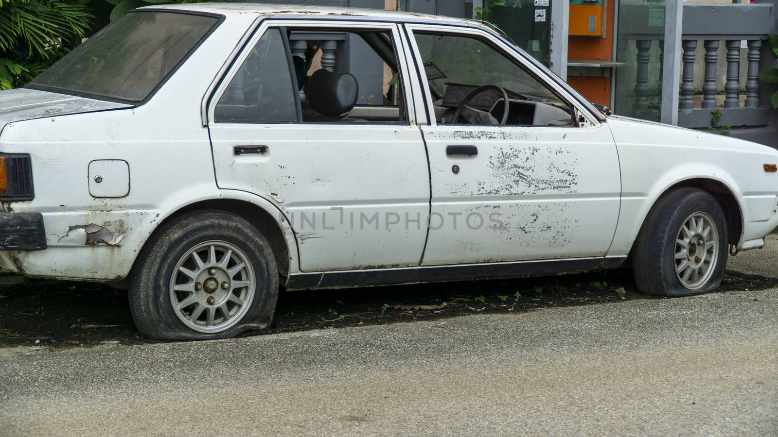 Old worn out and rusted abandoned car with flat tyre by sonandonures