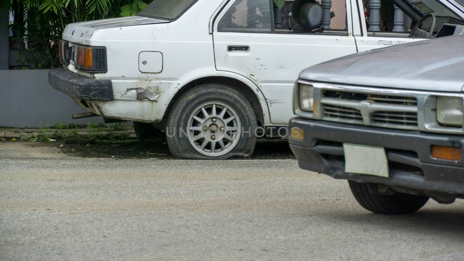 Old worn out and rusted abandoned car with flat tyre by sonandonures