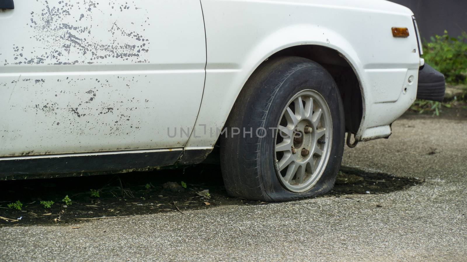 Old worn out and rusted abandoned car with flat tyre