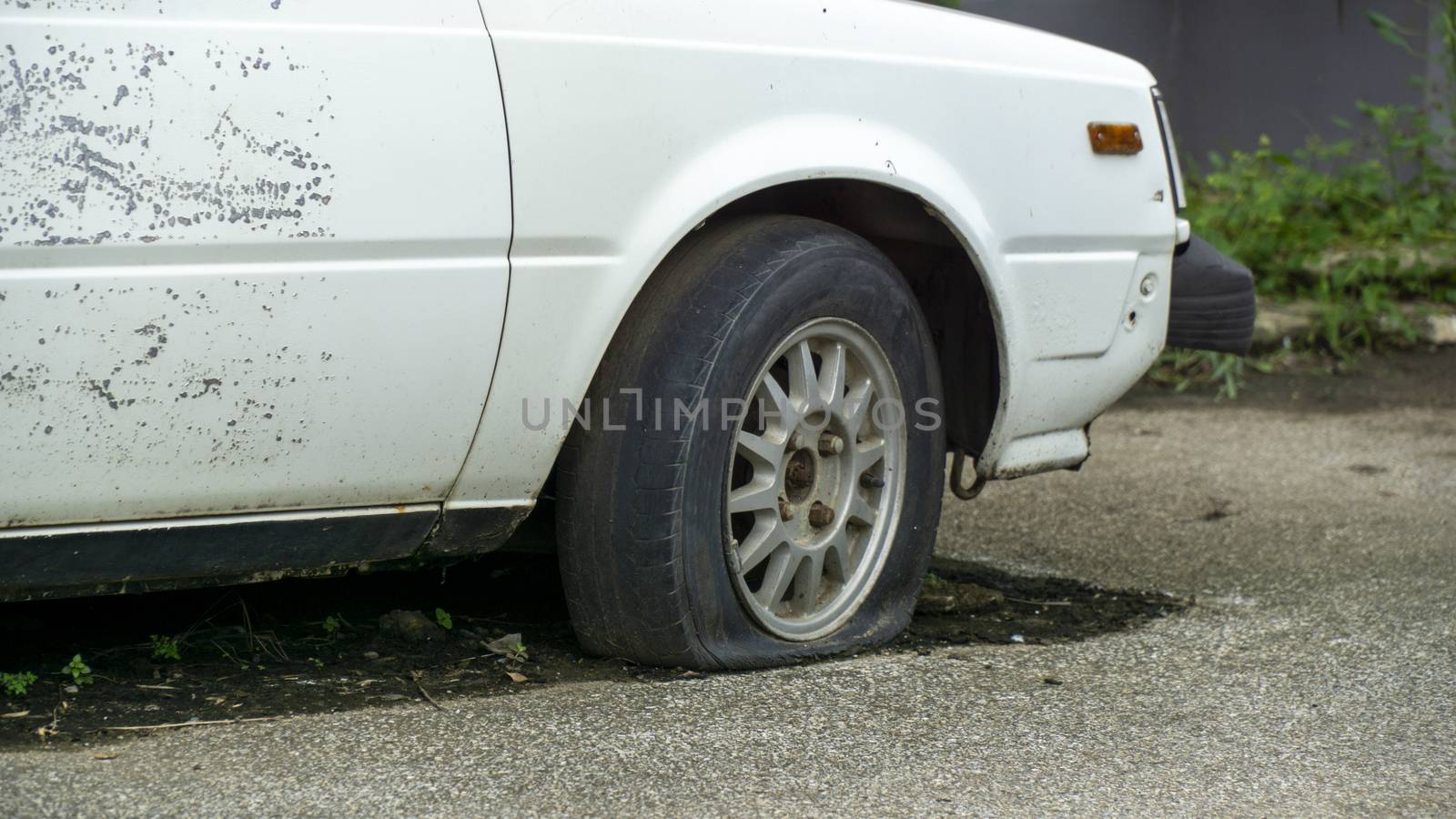 Old worn out and rusted abandoned car with flat tyre