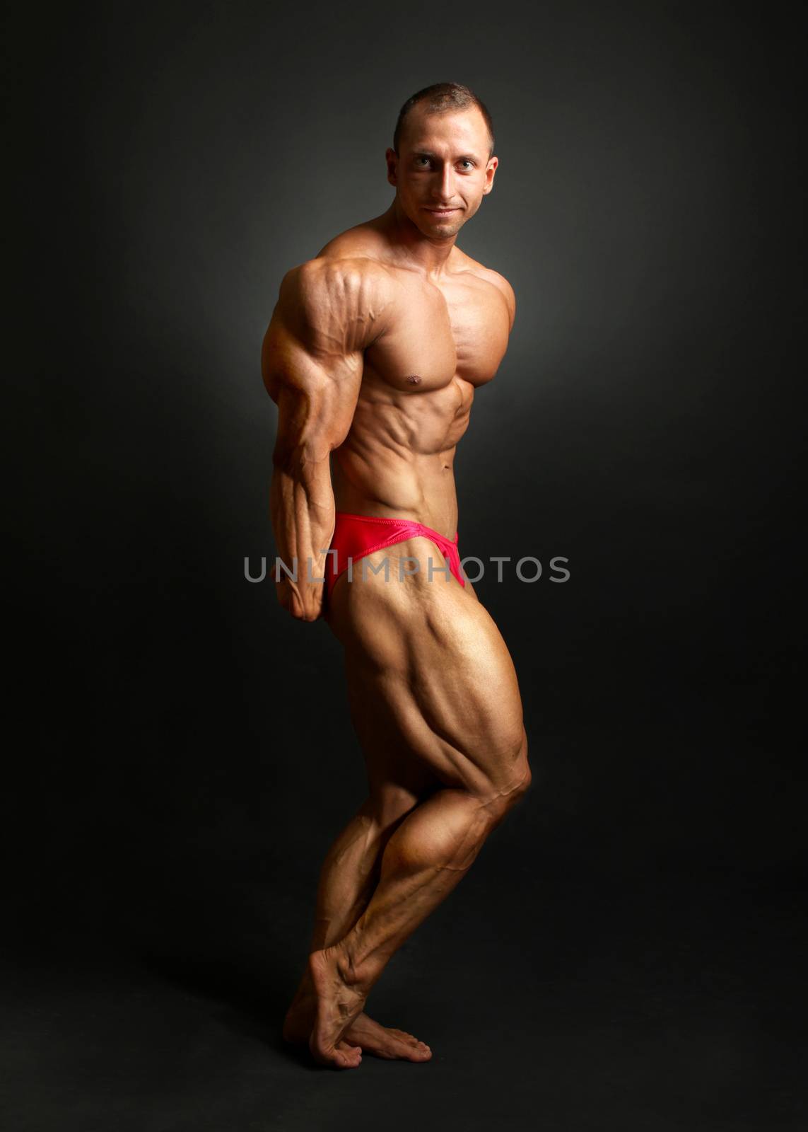 Studio shot of male bodybuilder posing, showing front muscles, h by Ivanko