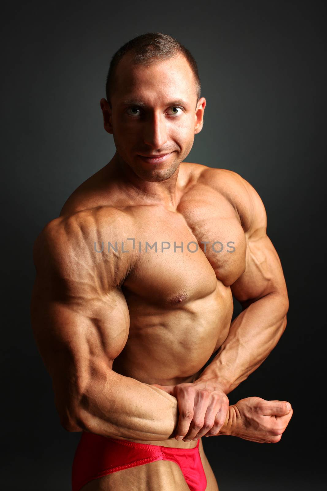 Studio shot of young male bodybuilder posing, showing his front  by Ivanko