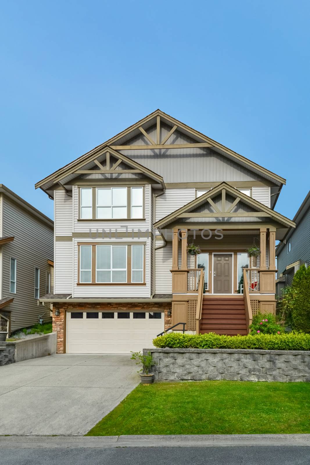 Main entrance of residential house with concrete driveway and small front yard on land terrace. 3 levels family house with porch and doorsteps