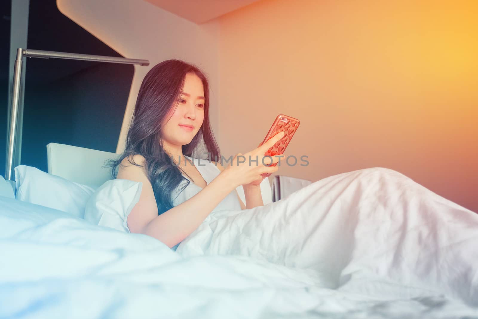 Yound woman using smart phone on the bed  by Surasak