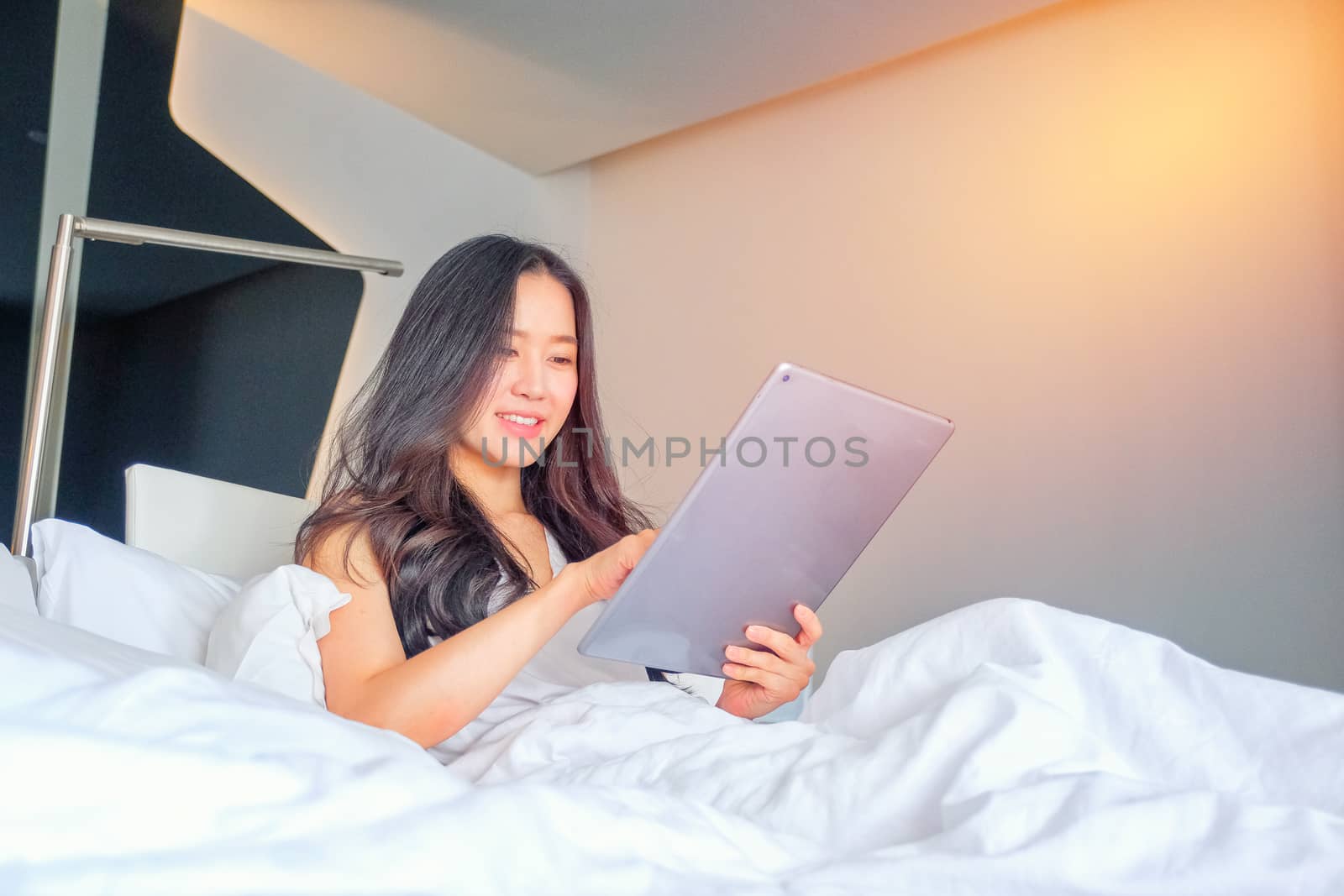 Yound woman using tablaet on the bed  by Surasak