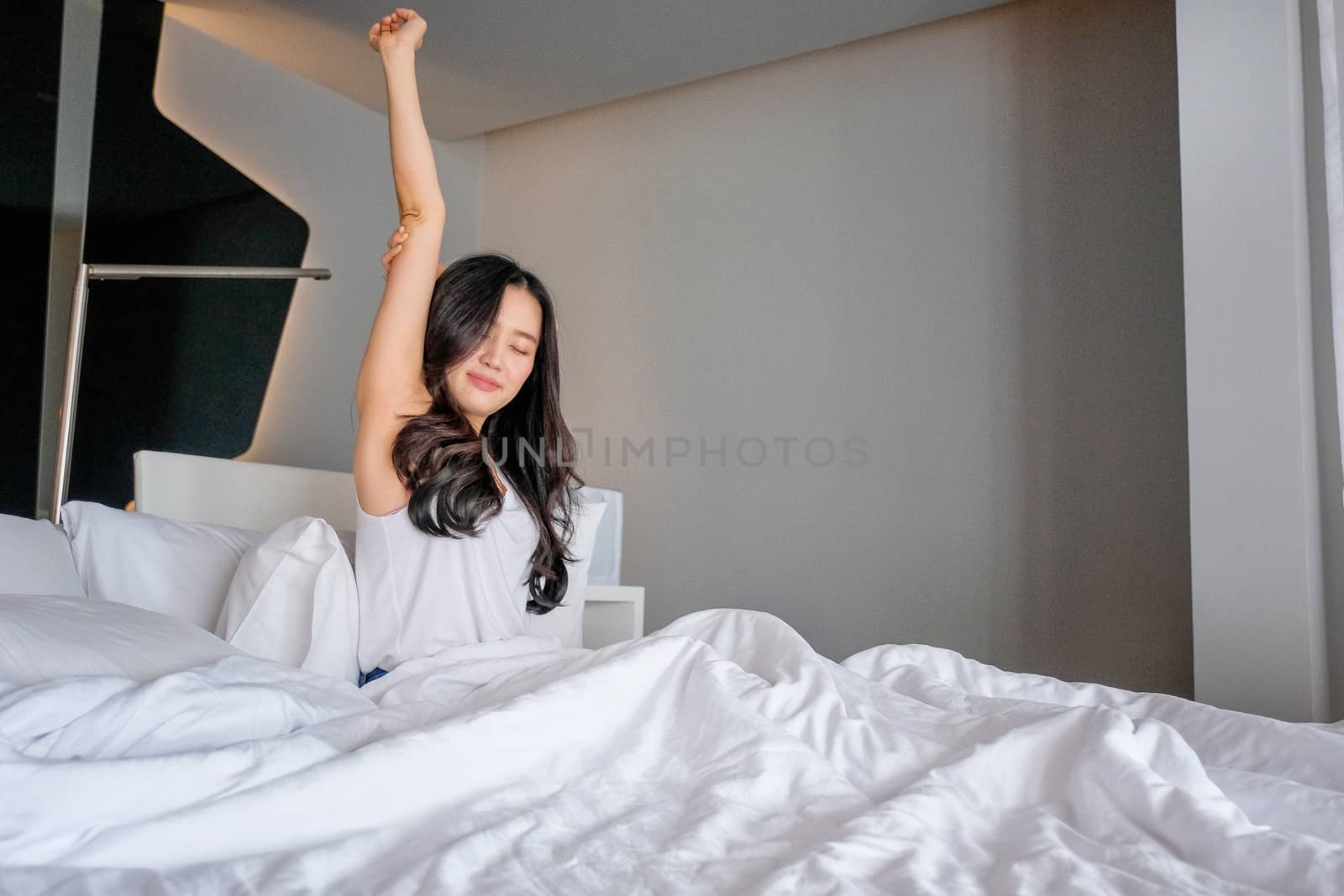 Woman stretch herself out after waking up in the morning by Surasak