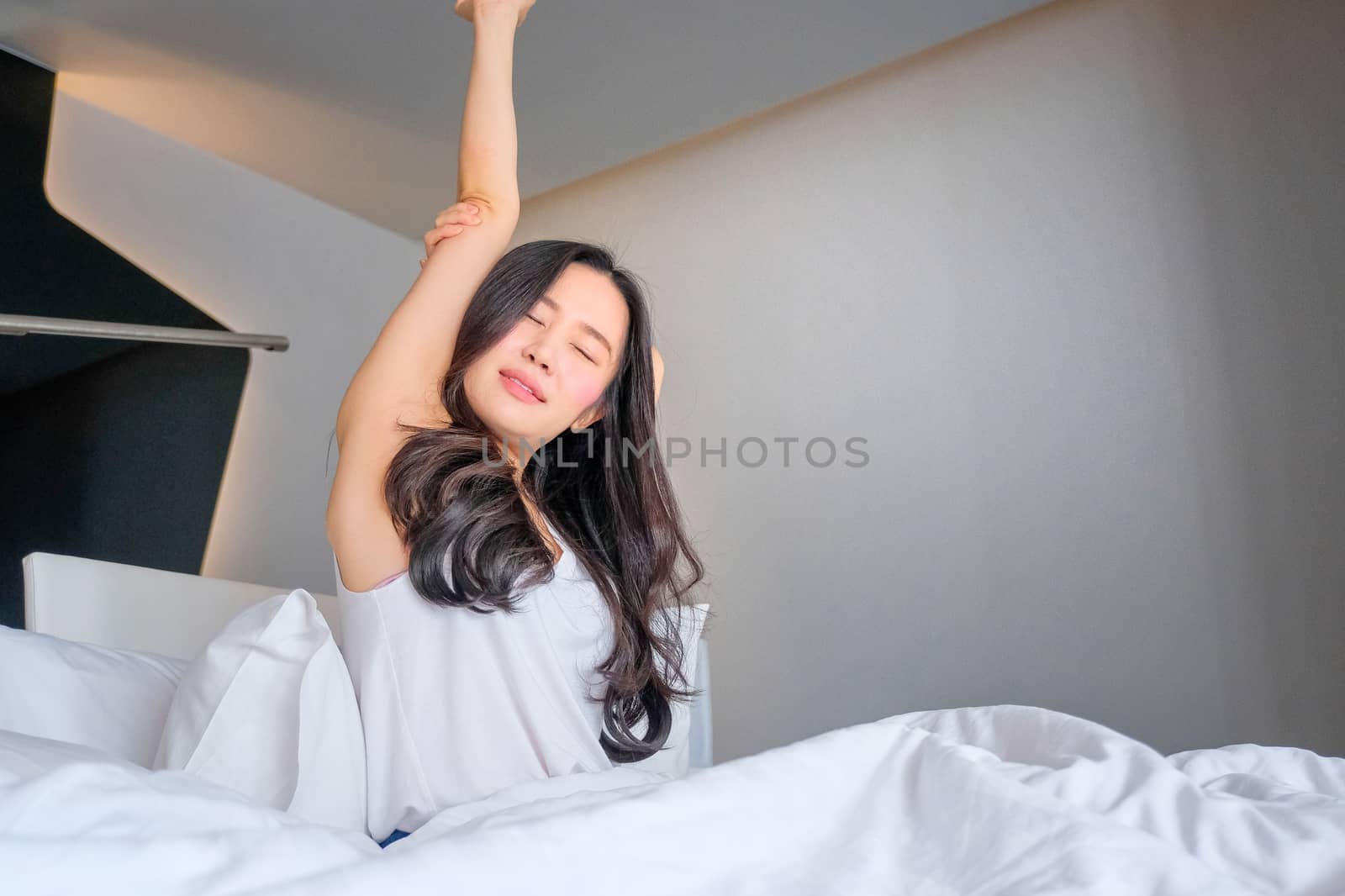 Woman stretch herself out after waking up in the morning by Surasak