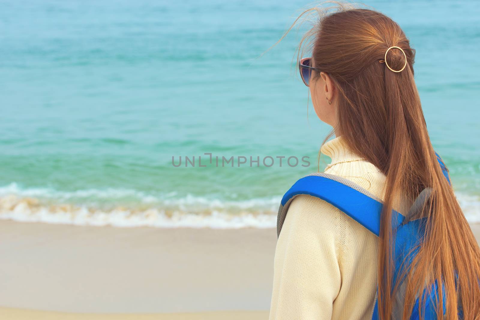Girl looks at the sea. Girl with backpack. Young woman traveler