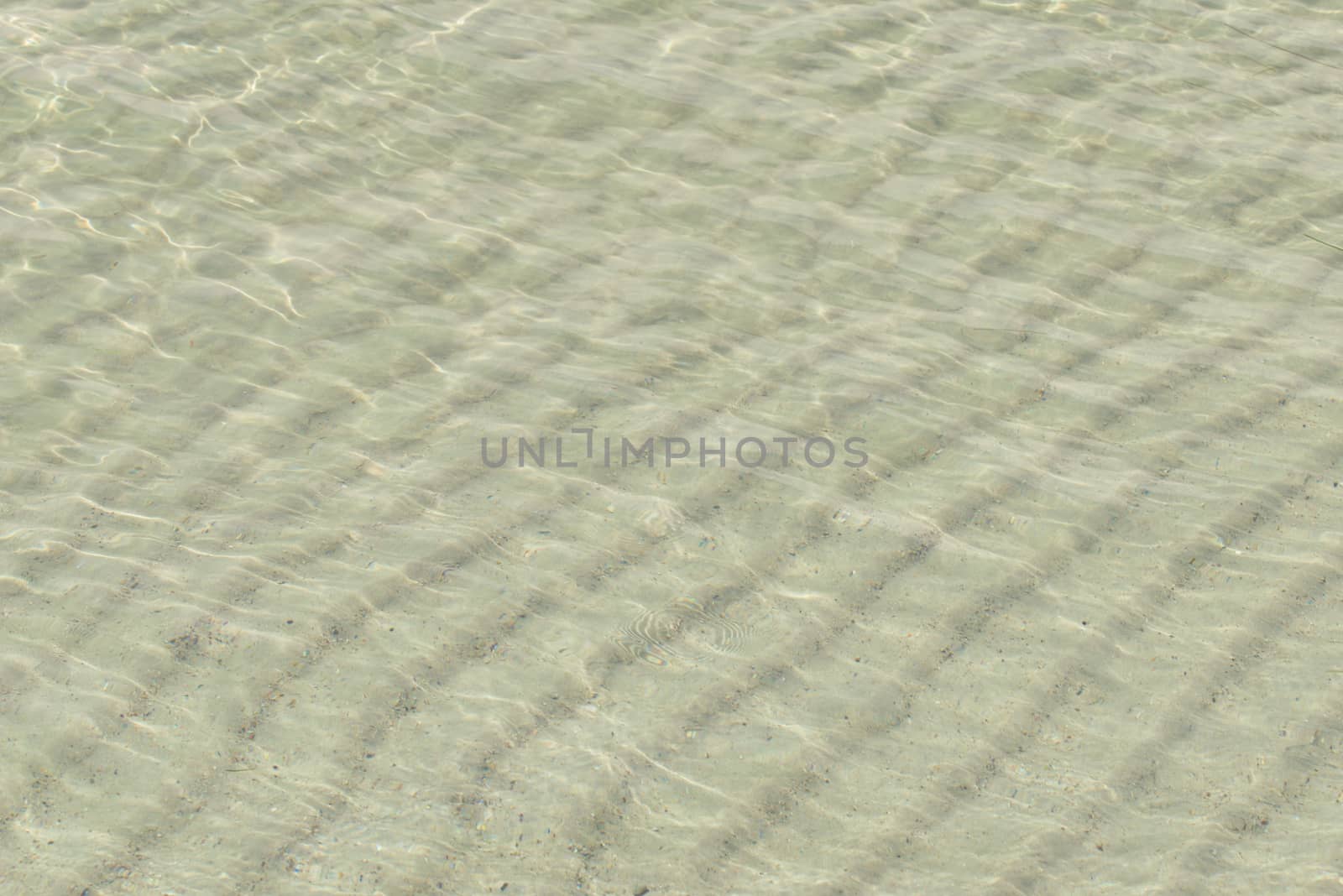 Sand under water. Glare on the sea surface