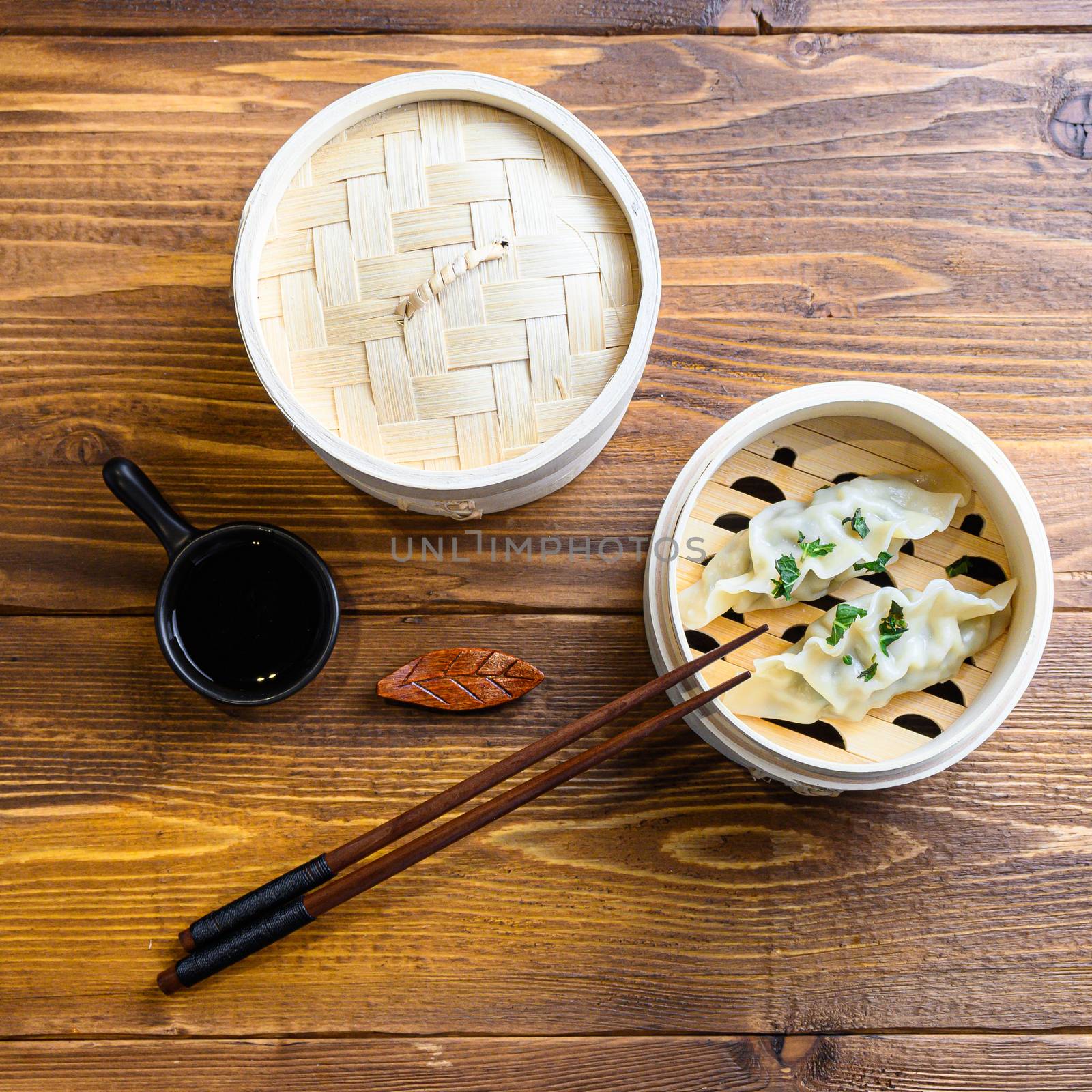 fresh boiled gyoza dumplings in wooden steamer with chopsticks soy sauce Chinese Traditional cuisine top view by Ilianesolenyi